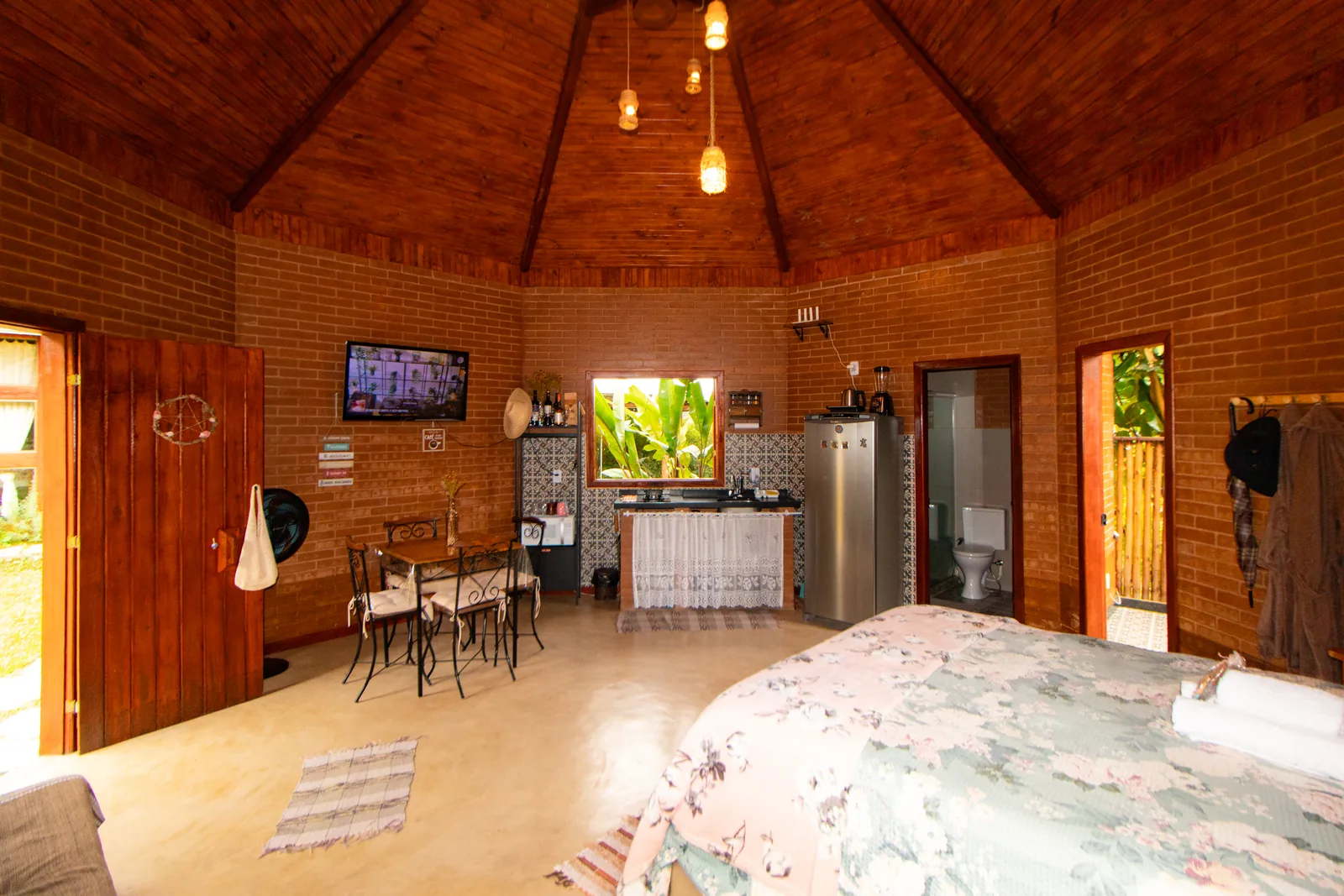 Interior da Cabana Estrela com planta redonda, teto de madeira em cúpula, cama de casal, copa e banheiro integrados