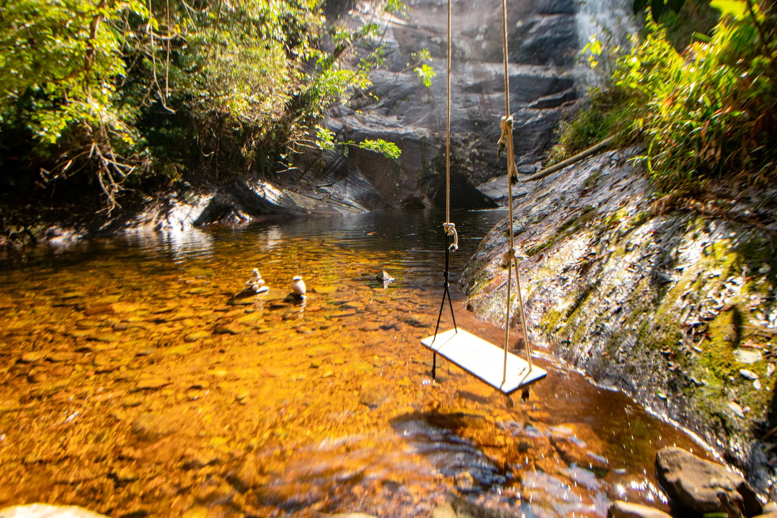 Cabana Lua e Cabana Estrela lado a lado no quintal gramado, com fogueira de pedras e balanço, sob o céu azul